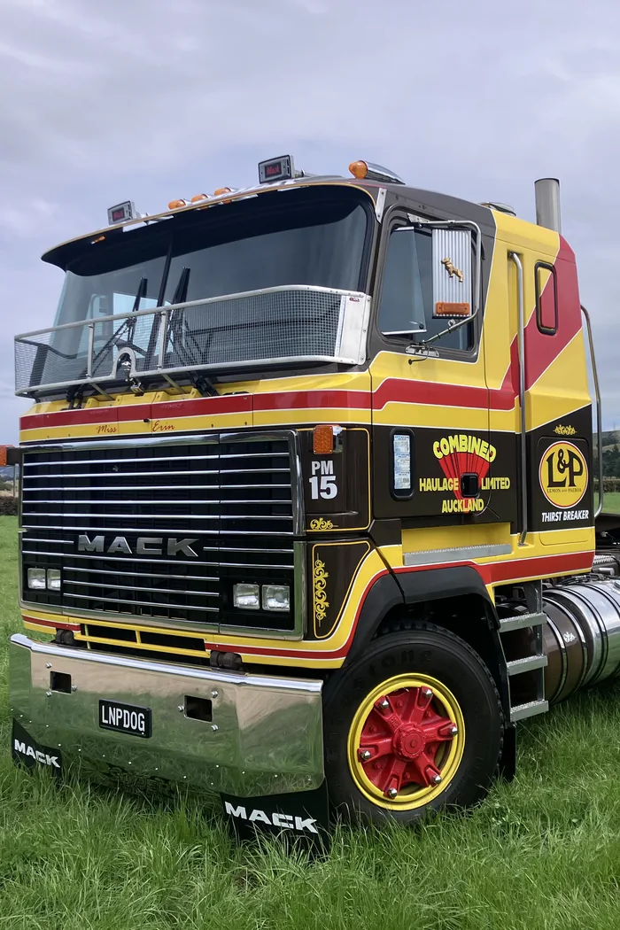 A restored Mack Ultra-Liner cab-over in yellow, red and brown L&P Thirst Breaker livery, parked in a paddock