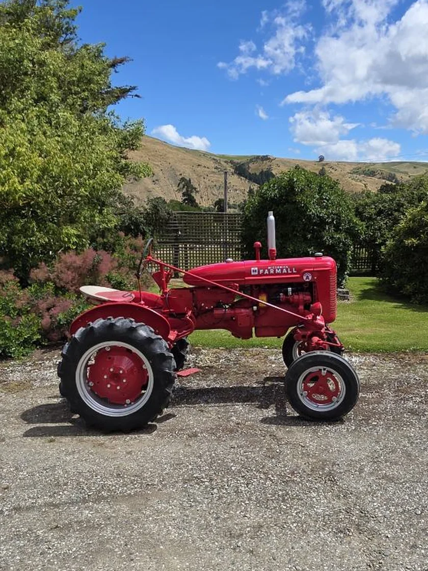 A restored McCormick Farmall Cub tractor parked on gravel with dry Central Otago hills behind