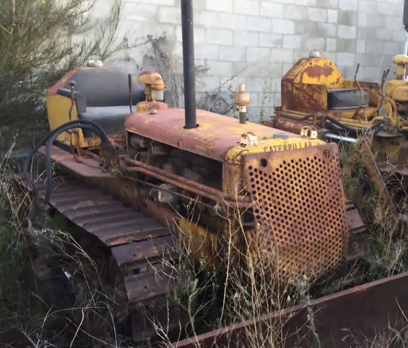 An unrestored Caterpillar D2 sitting in long grass