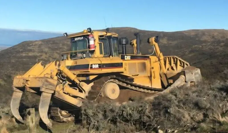 A Caterpillar D8R bulldozer with a ripper, working a hillside
