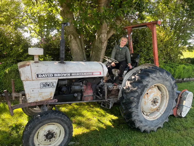 A white David Brown 880 Selectamatic with its driver, under trees