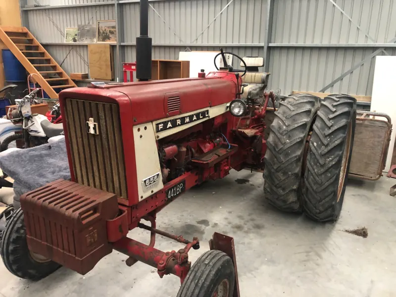 A red Farmall 656 with dual rear wheels in a shed