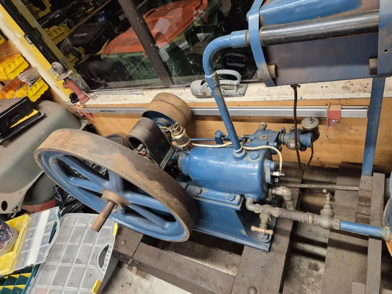 A blue 1907 Gardner 3hp stationary engine with its flywheel