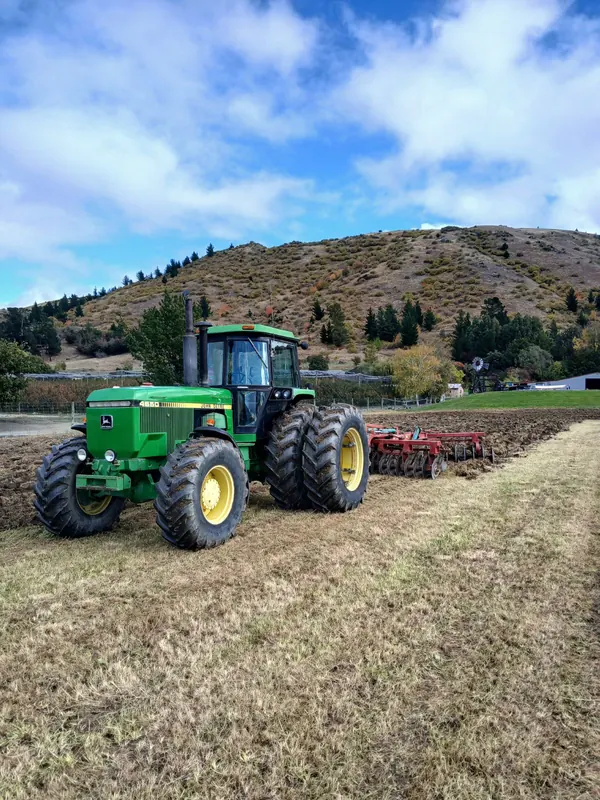 A John Deere 4650 working a paddock below a Central Otago hill