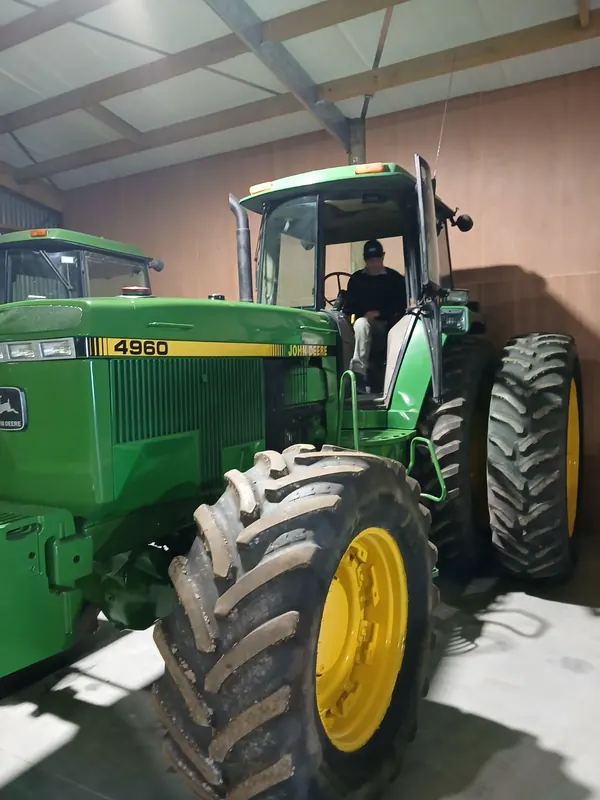 A John Deere 4960 parked in a shed