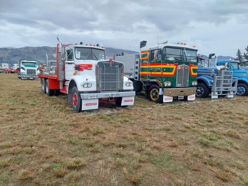 A white Kenworth W924 lined up with other classic trucks on grass