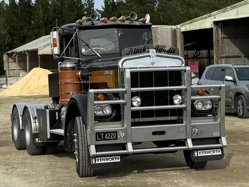 A black and chrome Kenworth W924R tractor unit outside a shed