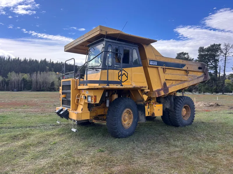 A yellow Komatsu HD255 rigid dump truck on a grass yard
