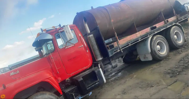 A red Mack R606 tanker working on a rough track