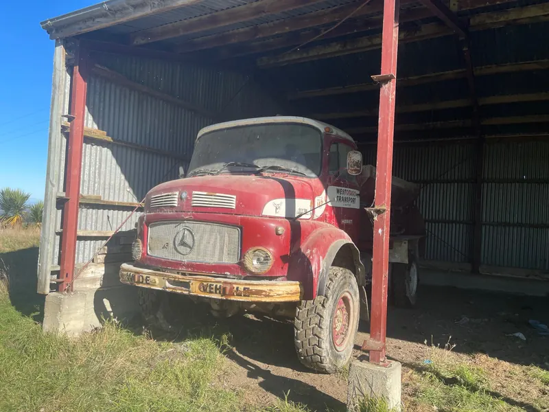 A red Mercedes-Benz 1113 truck in an open shed