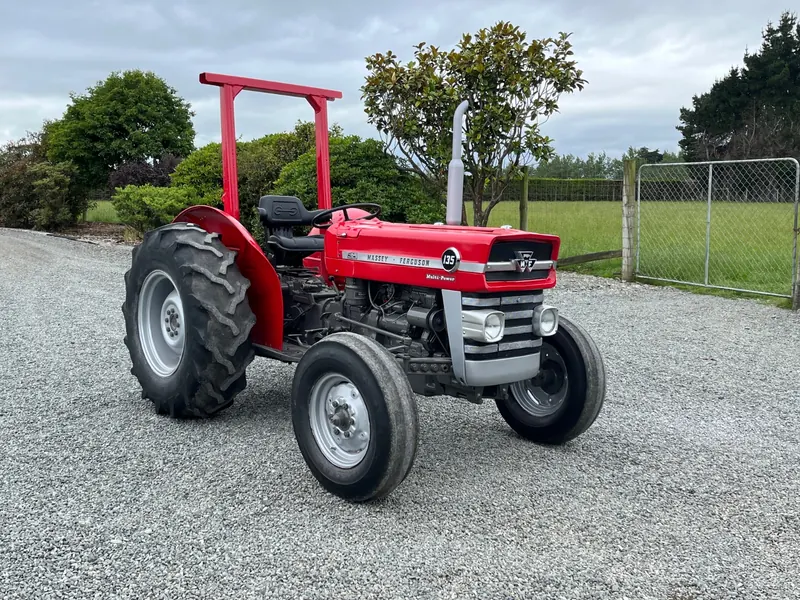A restored red Massey Ferguson 135 on a gravel drive