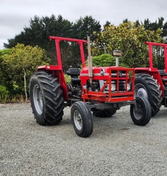 A red Massey Ferguson 185 with a roll bar, parked on gravel