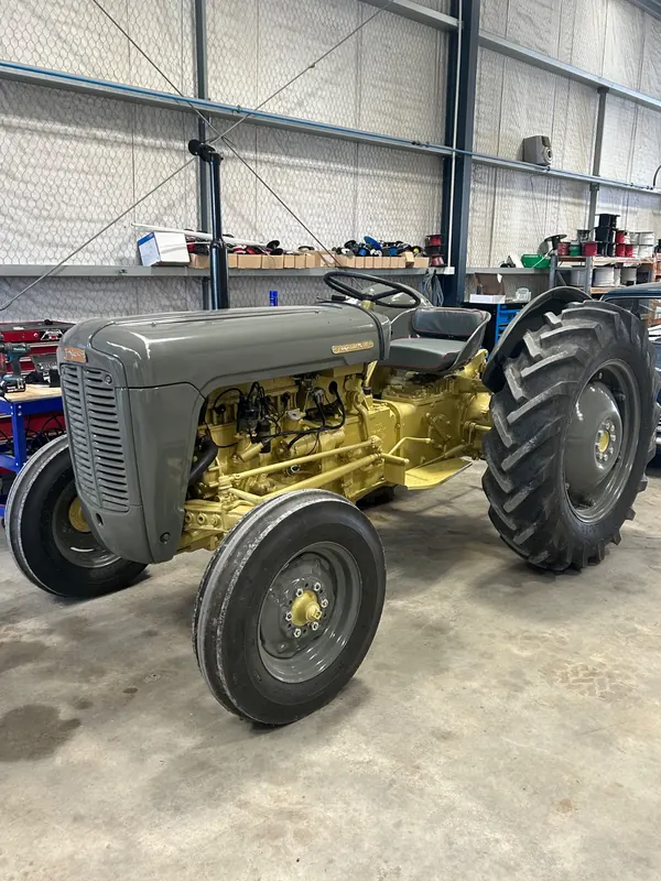 A grey and gold Massey Ferguson 35 parked in a shed