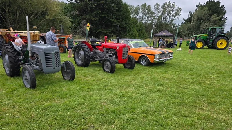 A red Massey Ferguson 35X beside a grey Fergie at a show