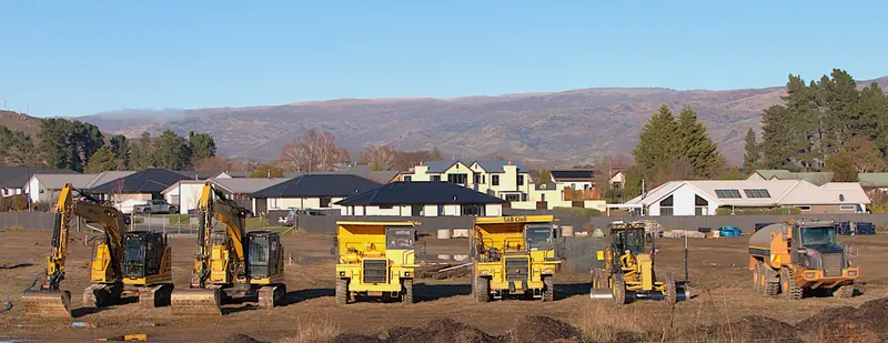 A line of diggers, dump trucks and a grader on a Central Otago subdivision
