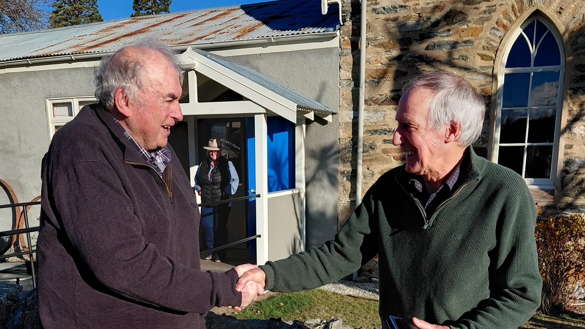 Peter Macdougall of Central Otago Tracks & Wheels shaking hands with Wayne Dixon of the Central Lakes Equestrian Club outside the Cromwell Racecourse building.